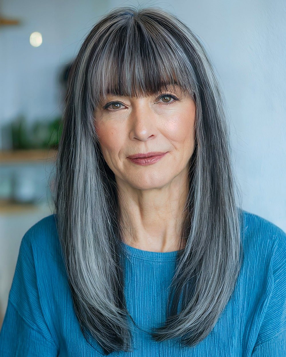 Long layered silver ash hairstyle with straight fringe and sleek finish for older women